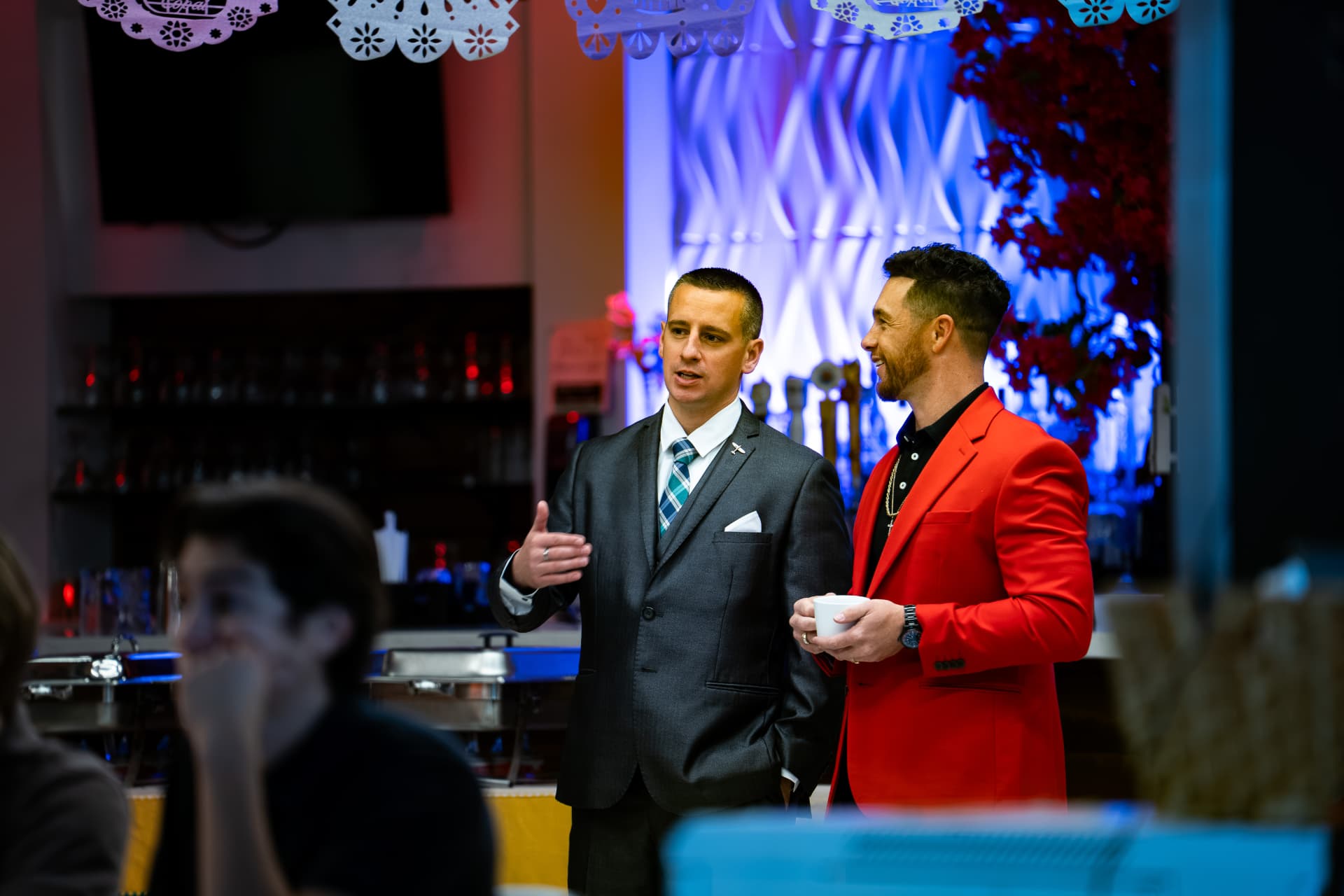 Two men in suits talking beside the bar at the October 2025 Vantage Business Mastery Workshop